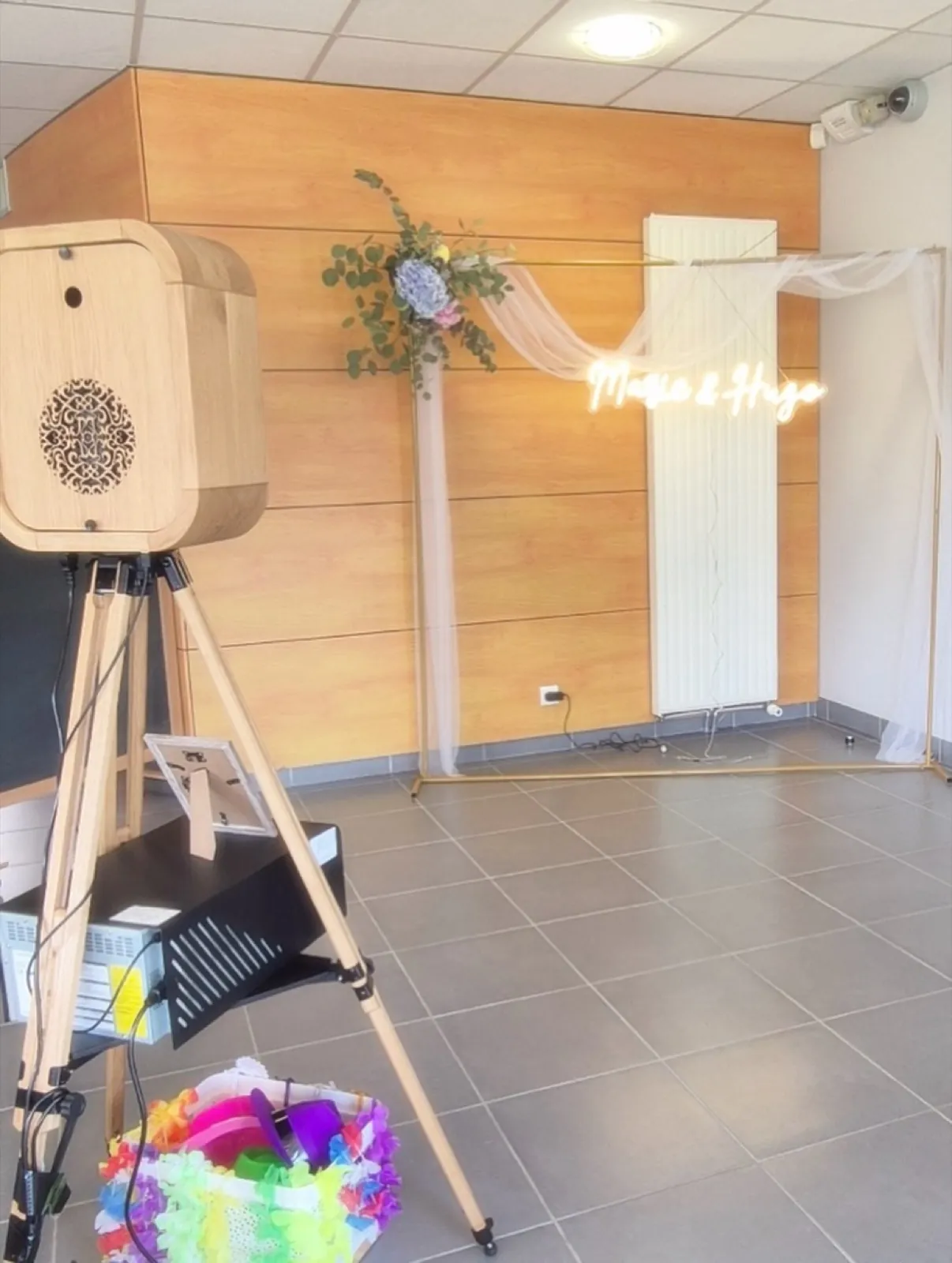 Photobooth de mariage avec enseigne néon personnalisée et toile de fond fleurie